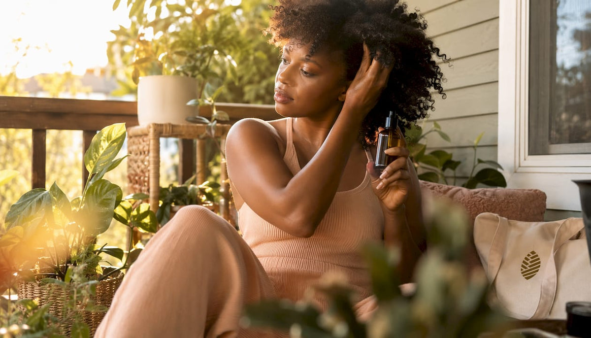 Woman applying natural oils to curly afro hair