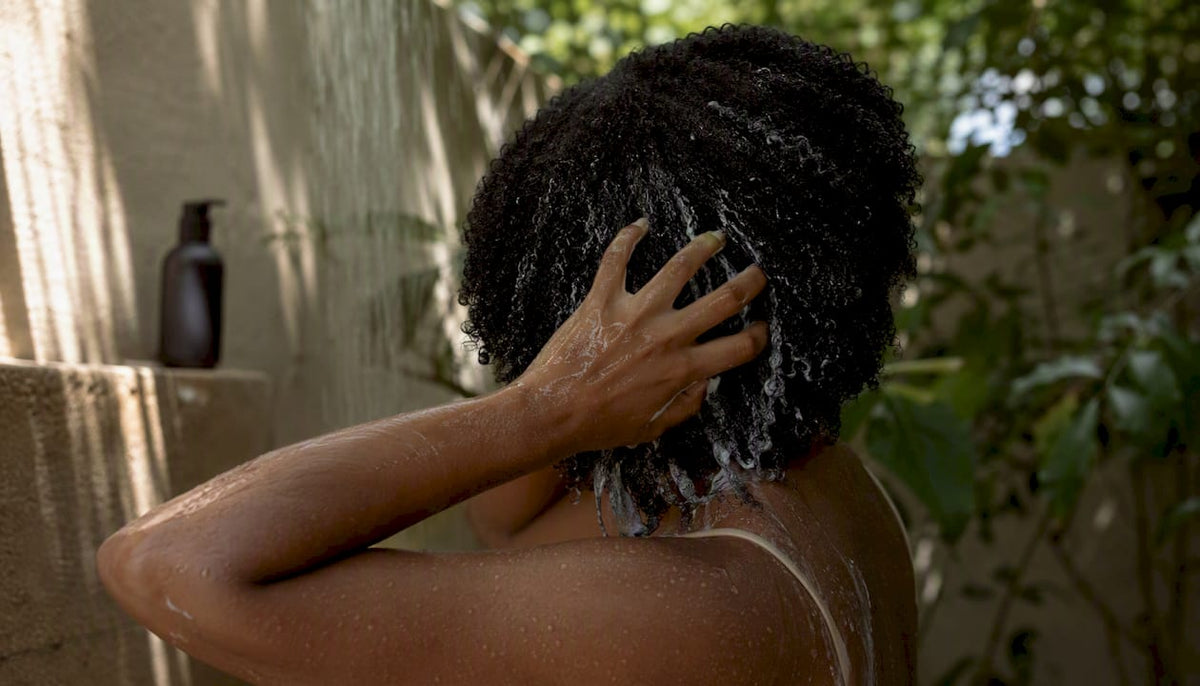 Hands applying conditioner to curly hair