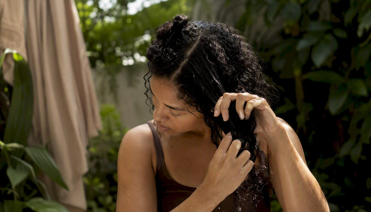 Woman sectioning curly hair in bathroom