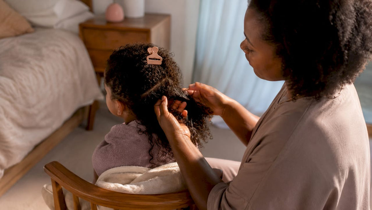 Parent gently detangling child's coily hair