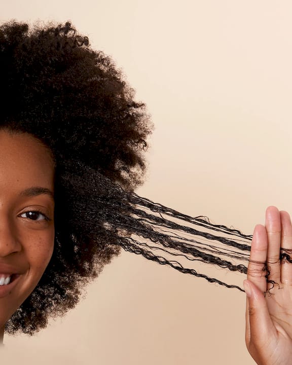 Woman moisturizing curly hair at bathroom vanity