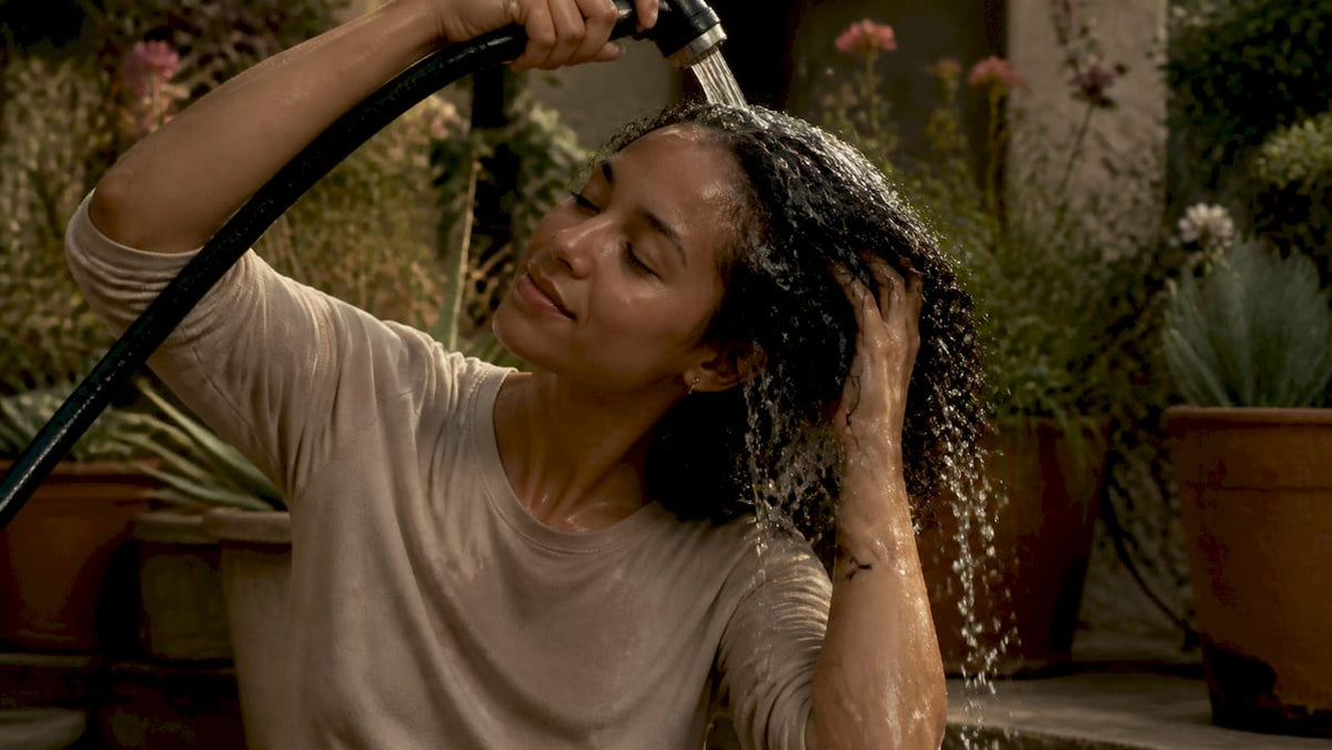 Curly hair rinsing under shower water