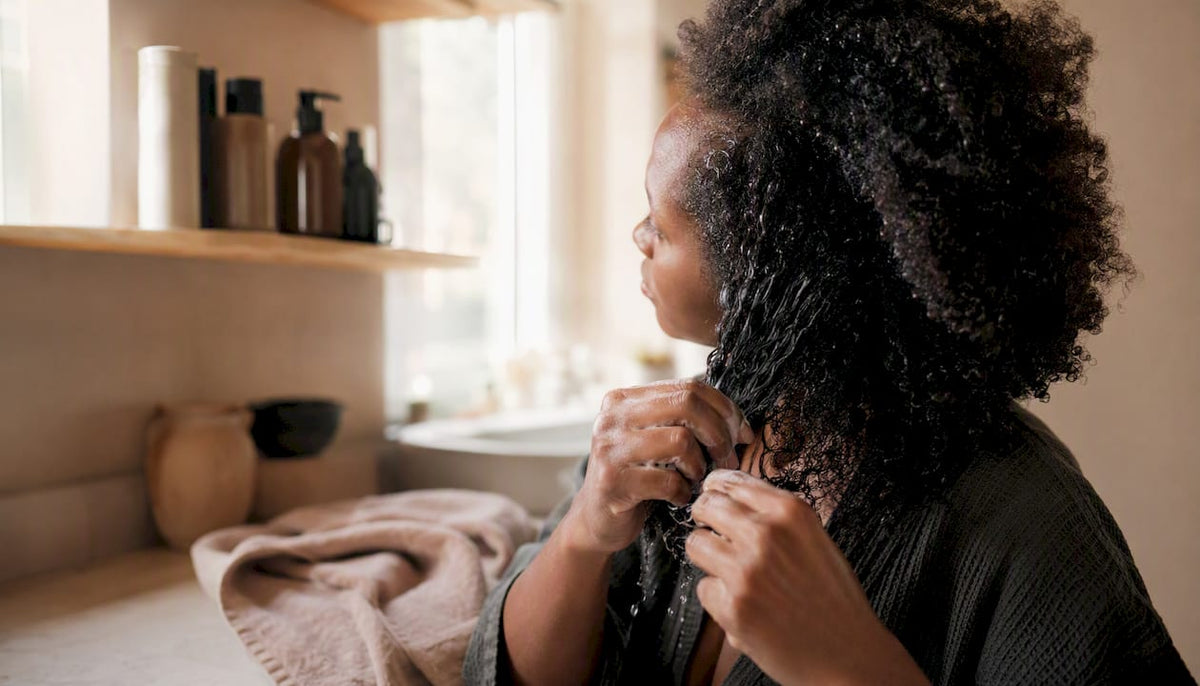 Hands detangling afro-textured hair wet with conditioner