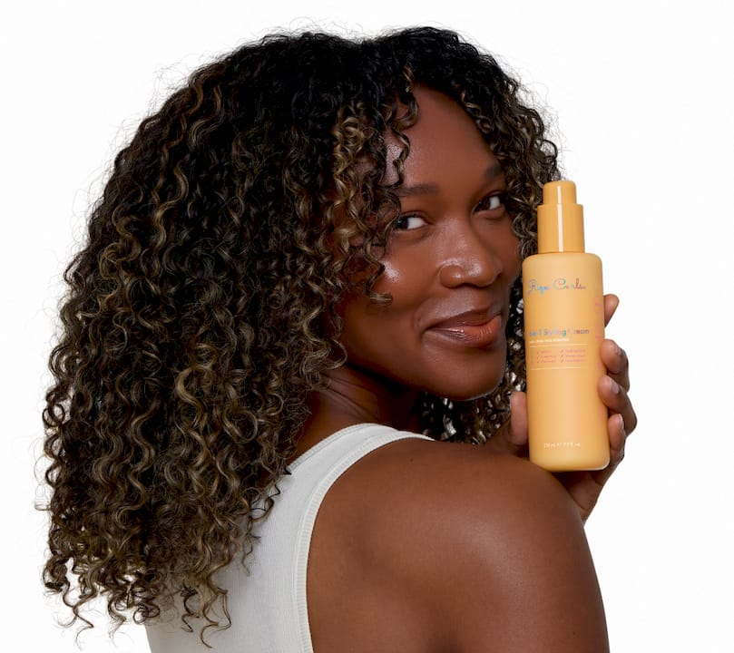 Young woman applying leave-in conditioner to curls