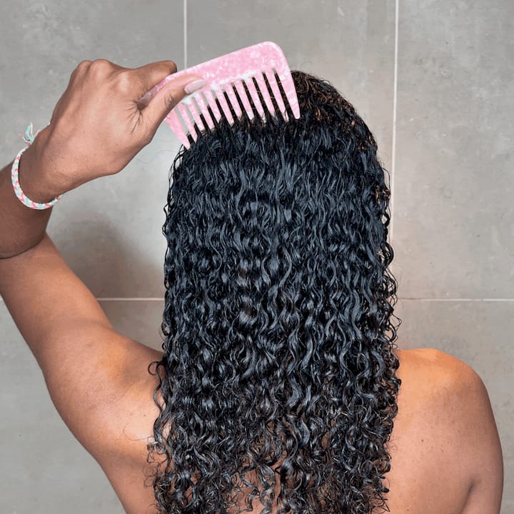 Woman gently conditioning defined curly hair