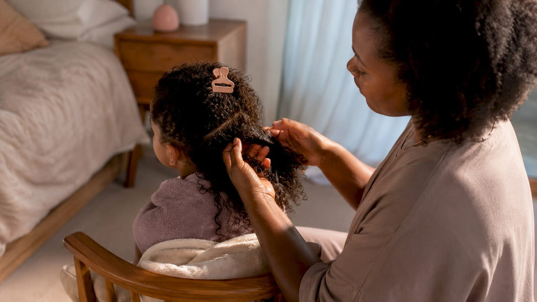Parent gently detangling child's coily hair