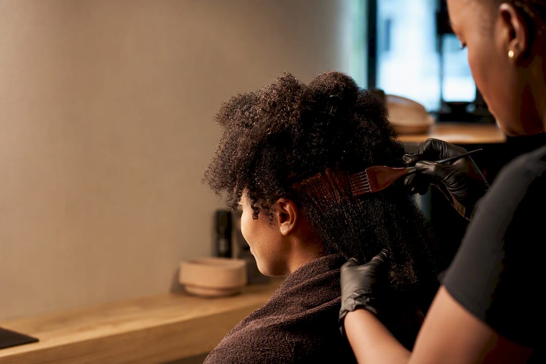 Colorist applying dye to coily hair