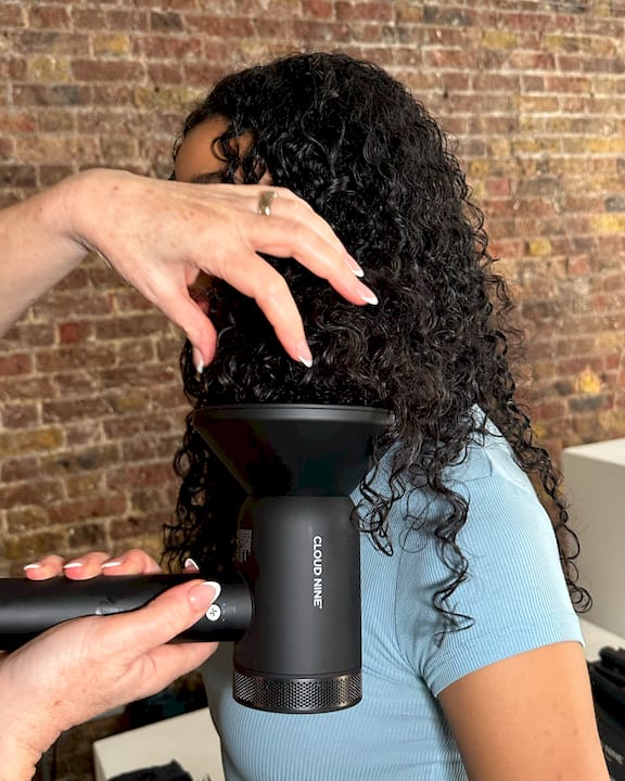 Woman diffusing wavy hair at home