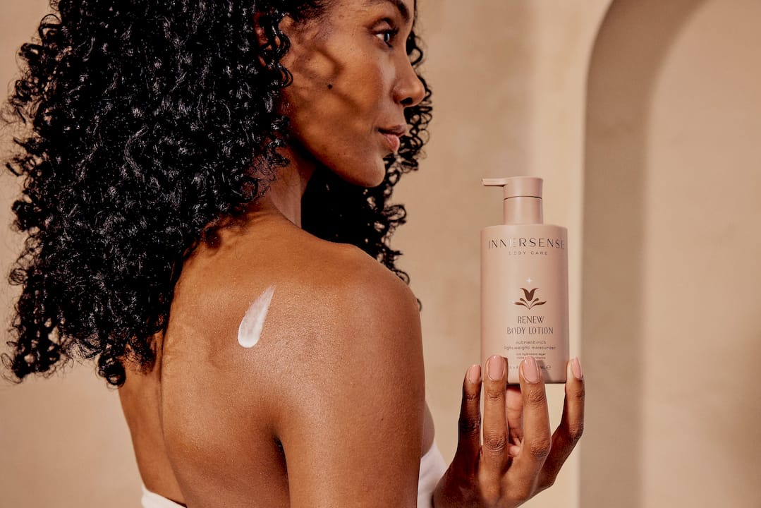 Woman with curly hair holding a bottle of cream