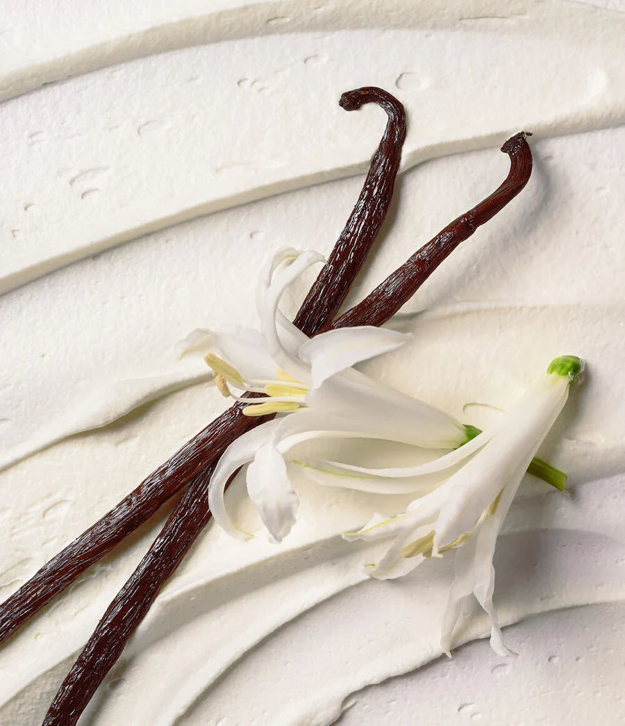 Vanilla beans and vanilla flower on a light wooden surface